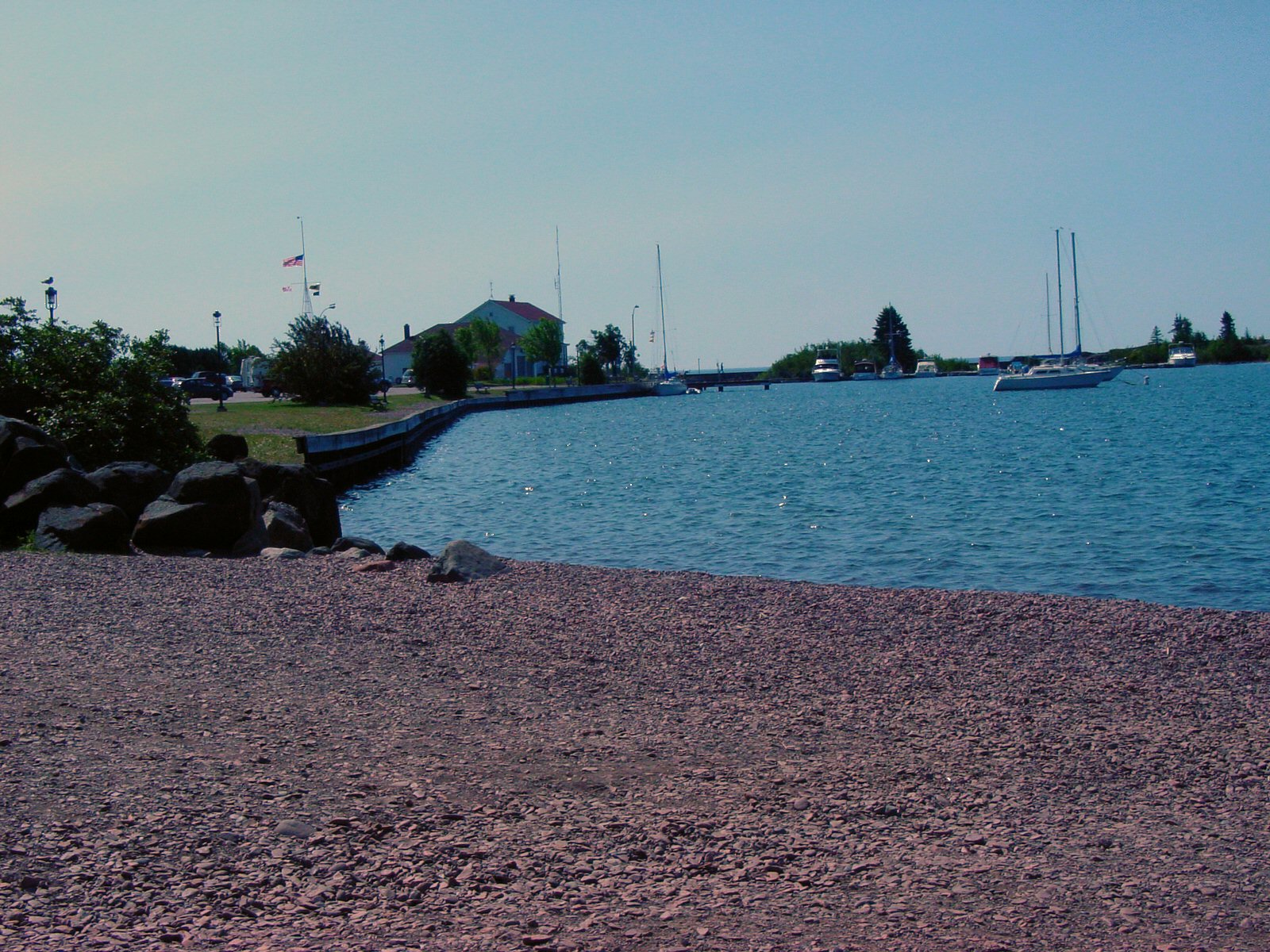 two canoes are on the water behind a rock bank