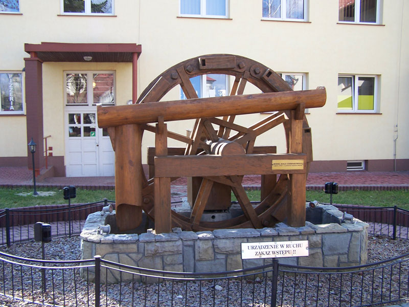 a wooden wheel that is on display in front of some buildings