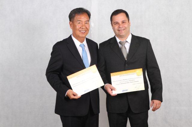 two men in business attire standing together with a cheque