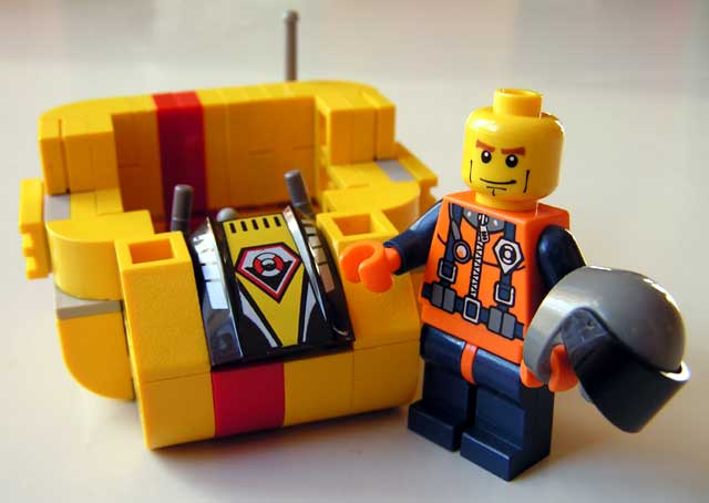 a yellow lego car with a toy man holding a piece of the car