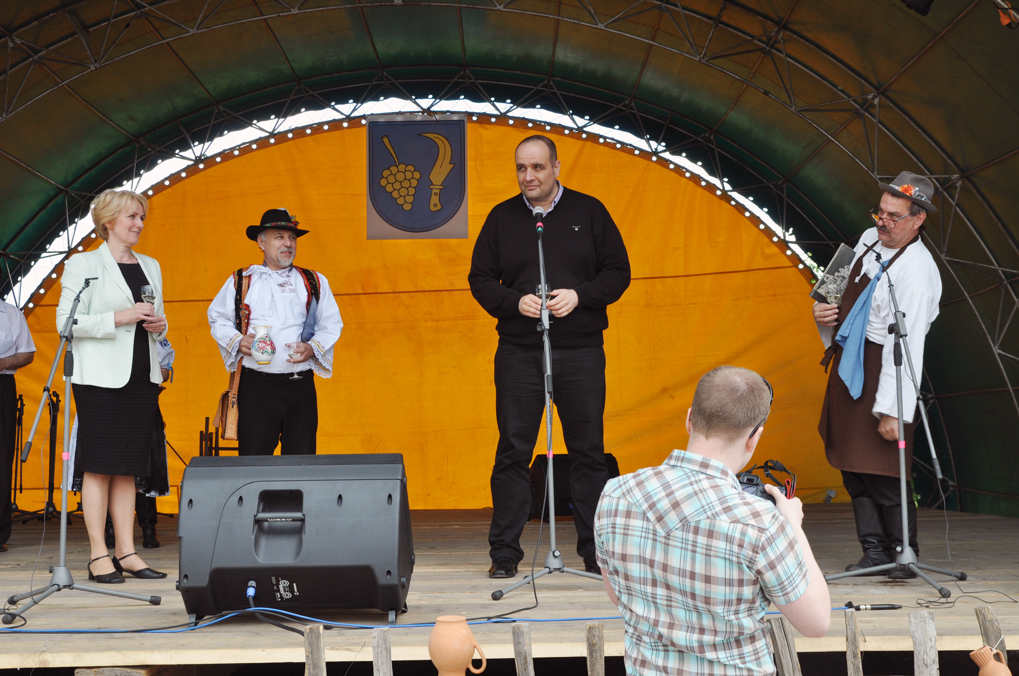 the men are singing at the stage and standing near their speakers