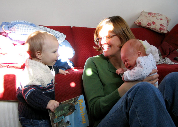 a woman is smiling while holding two babys
