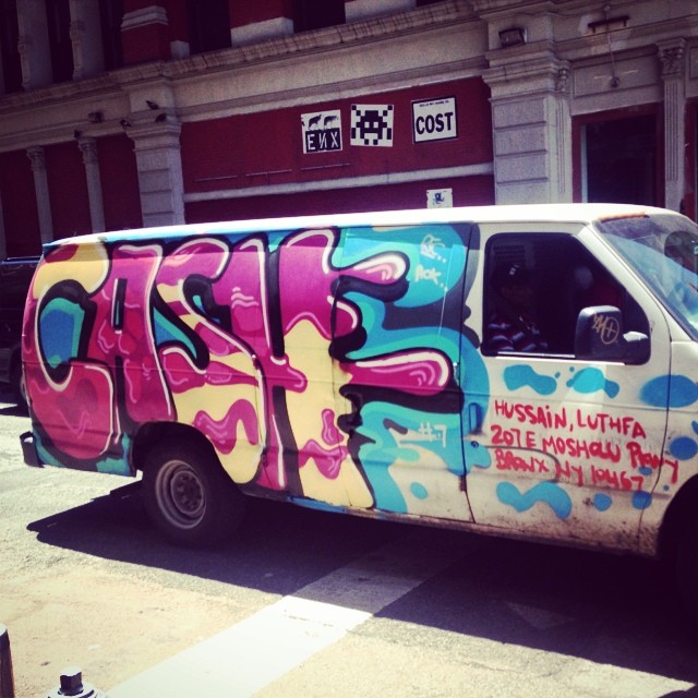 a van painted with spray paint sitting on the side of a road