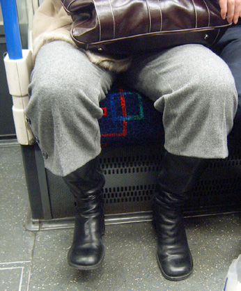 a woman is sitting down and wearing black boots