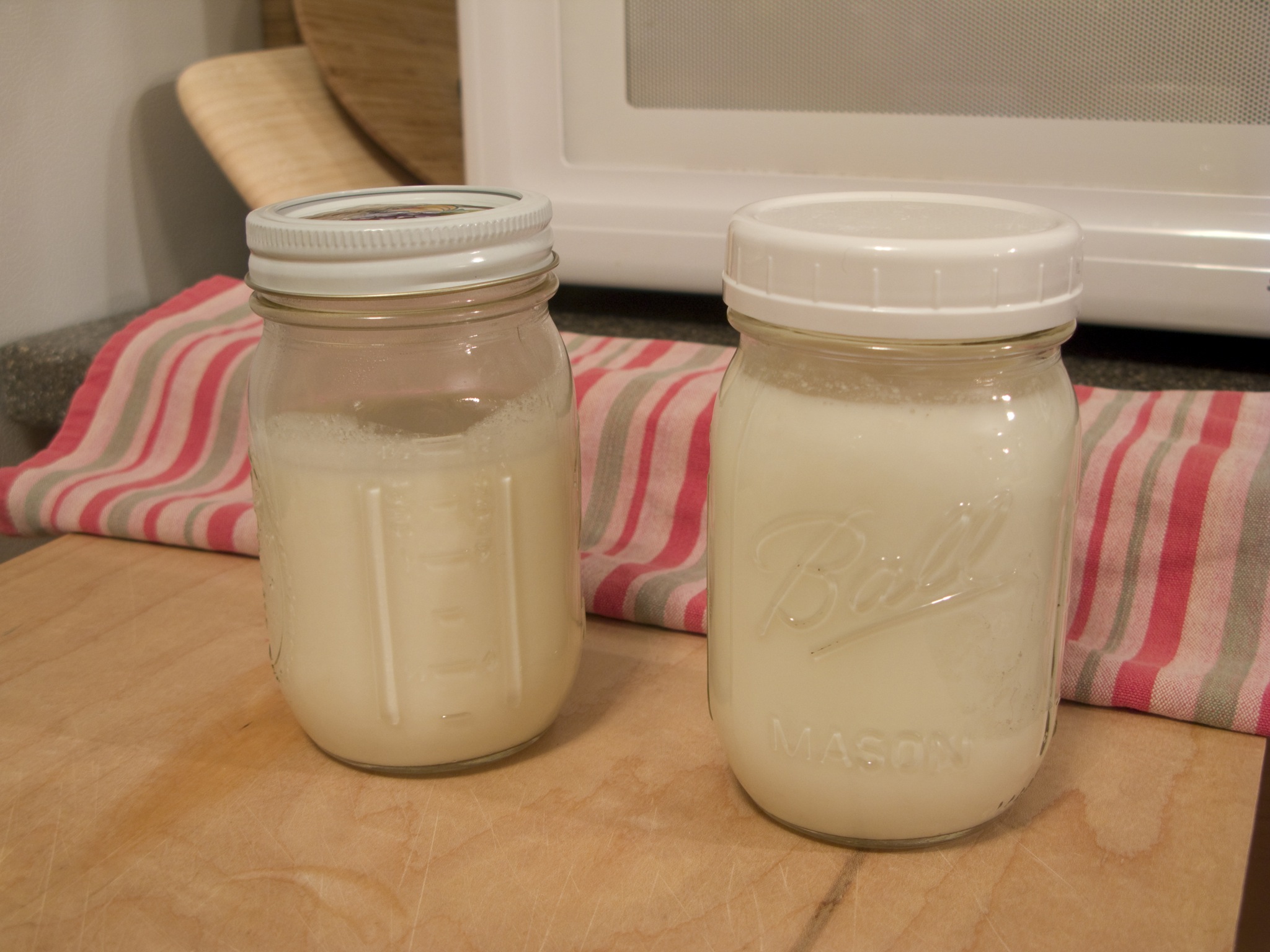 two jars filled with liquid sitting on a table