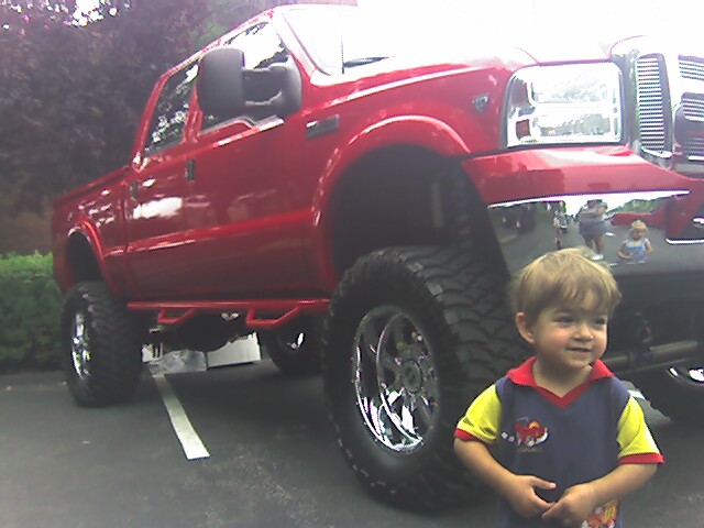 a  standing in front of a red pick up truck