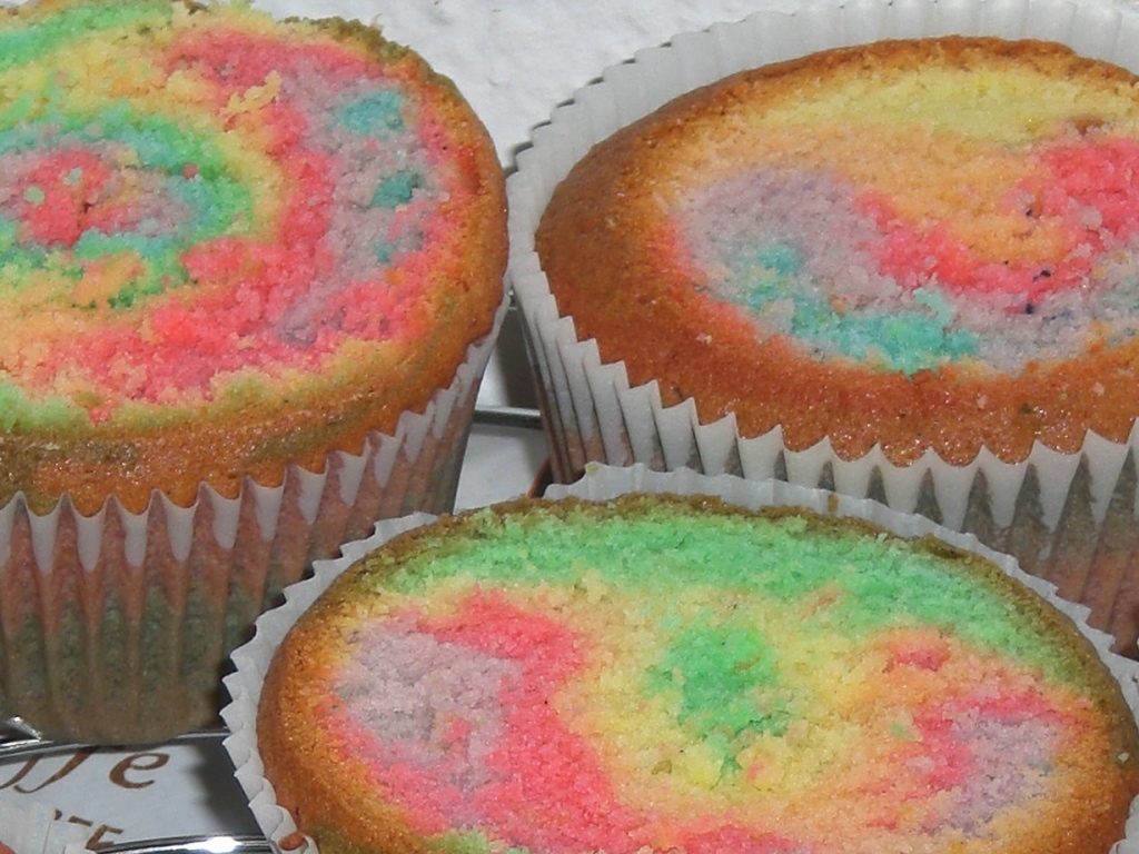 three brightly colored cupcakes are sitting on a cake tin