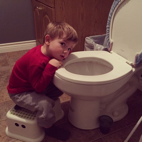 a little boy that is leaning on a toilet