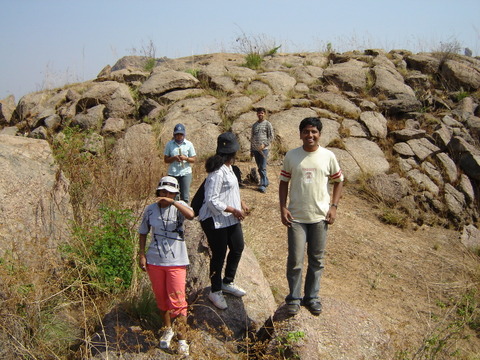 some people are standing near a rock hill