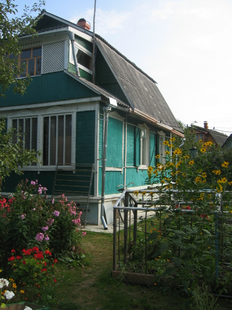 a green house sitting next to a lush green yard