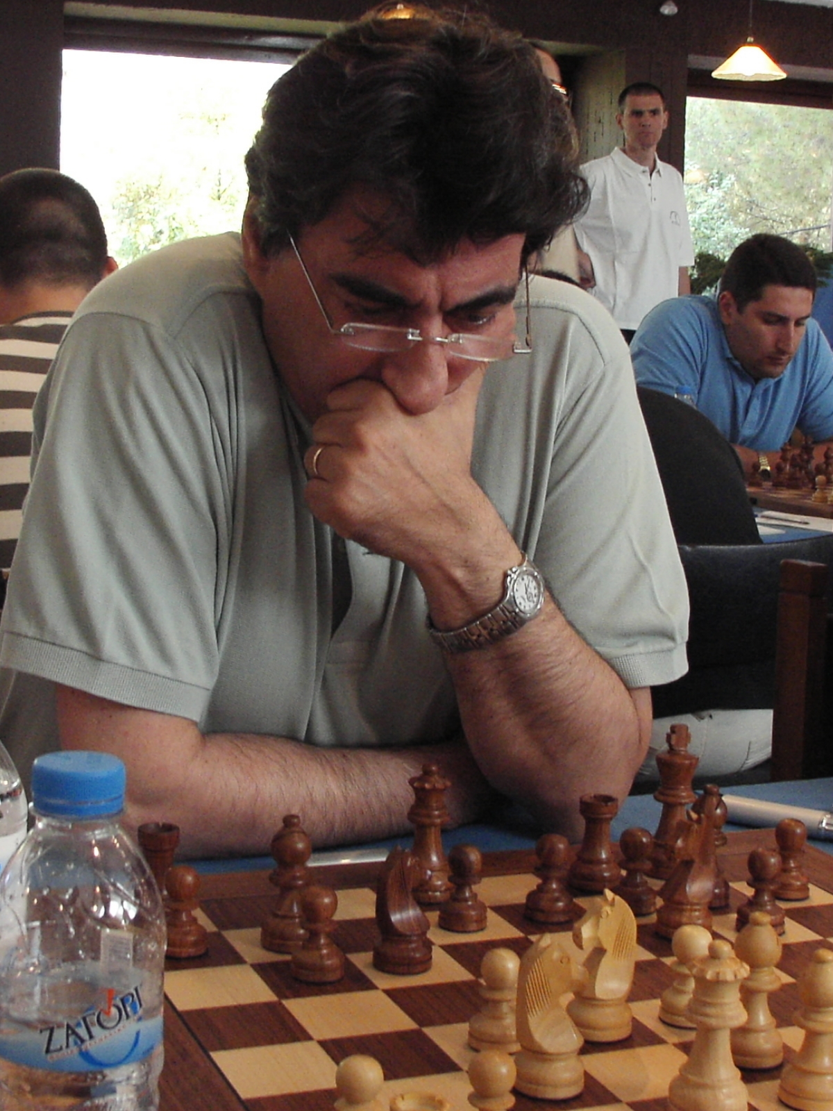 a man sitting at a table next to a chess board