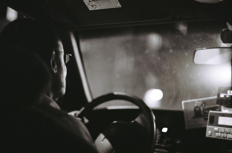 an older man drives a truck at night