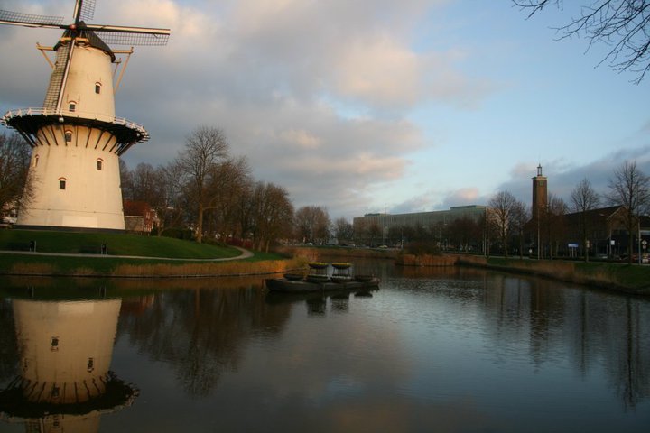 several boats float in the water below the windmill