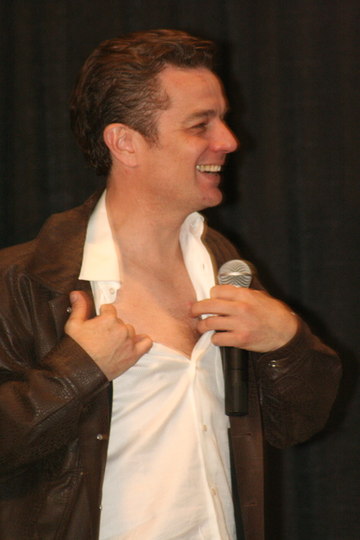 a man in white shirt and jacket talking on a microphone
