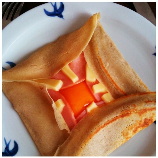 a white plate with pancakes cut in half and some tomato wedges