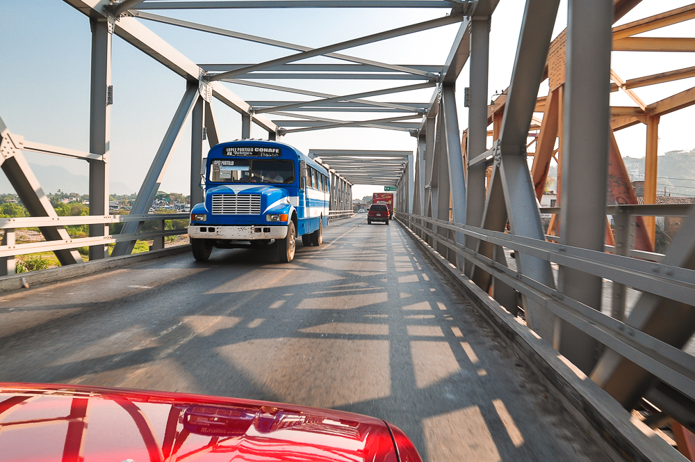 two large trucks driving down a road on top of a bridge