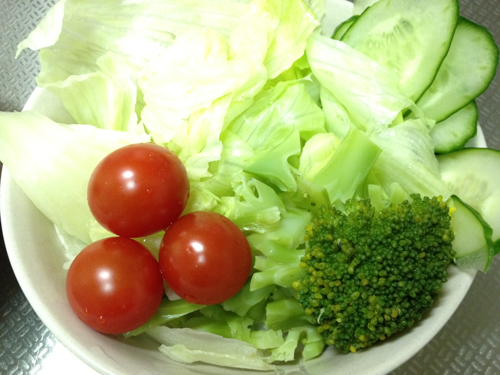 a white bowl with tomatoes, broccoli and lettuce