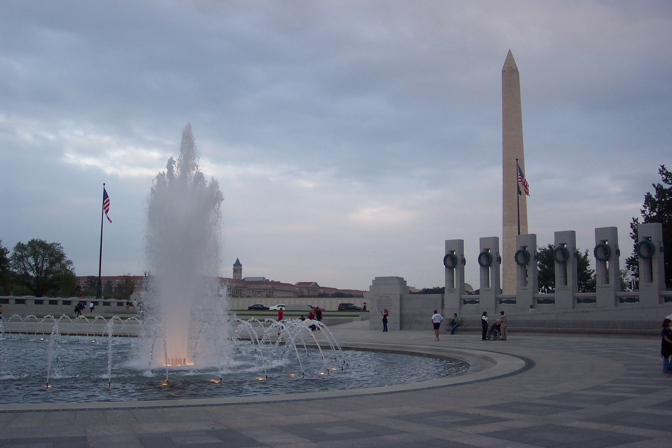 a bunch of people standing in front of a large fountain