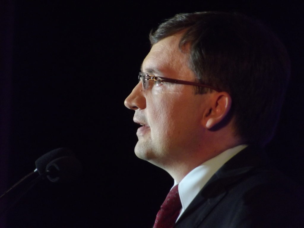 a man wearing glasses and a suit is giving a speech