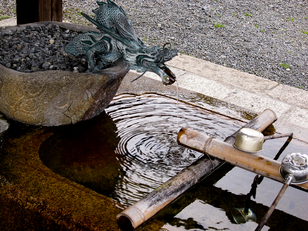 a statue of a frog sitting in a bowl of water