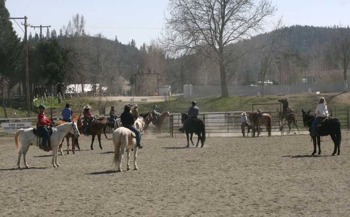 several people are riding their horses in an enclosure