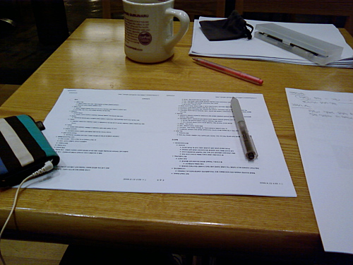a table with a coffee mug, paper and pen