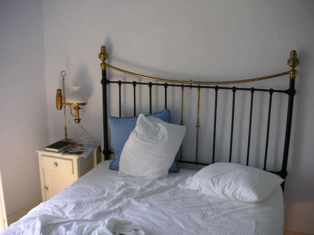 the bed has two white pillows and two gold headboards
