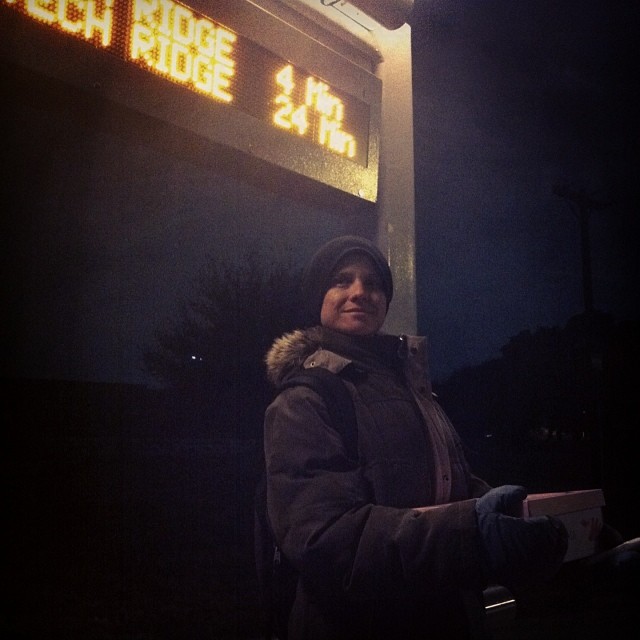a woman standing next to an electronic sign at night