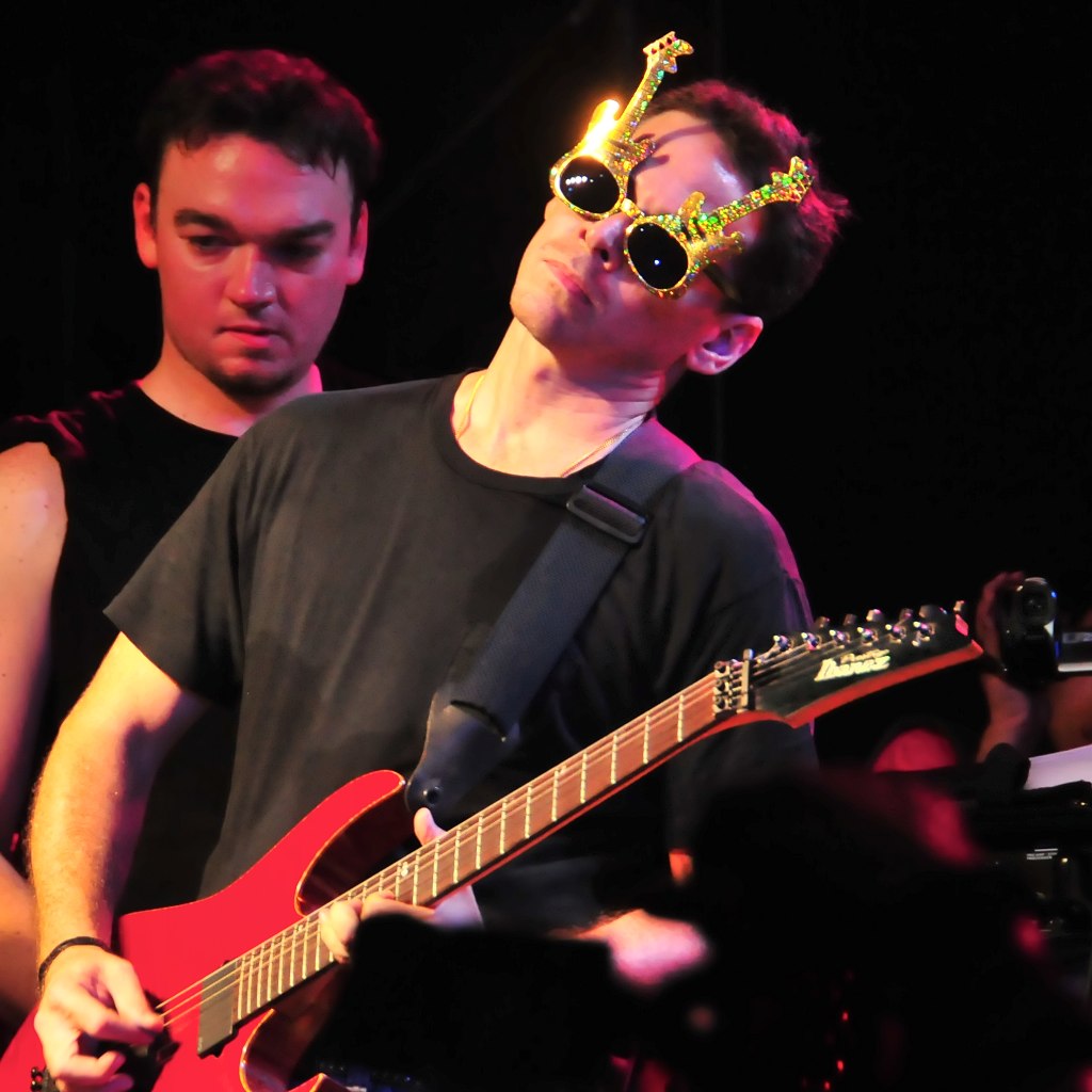 young adult with sunglasses and sunglasses playing guitar