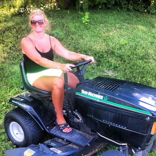a woman riding a ride on a lawn mower