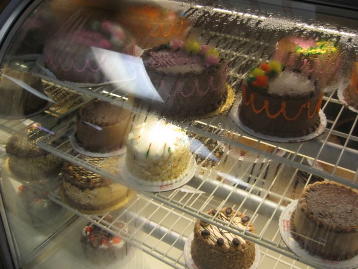 a bakery case with an assortment of cakes sitting on the shelves