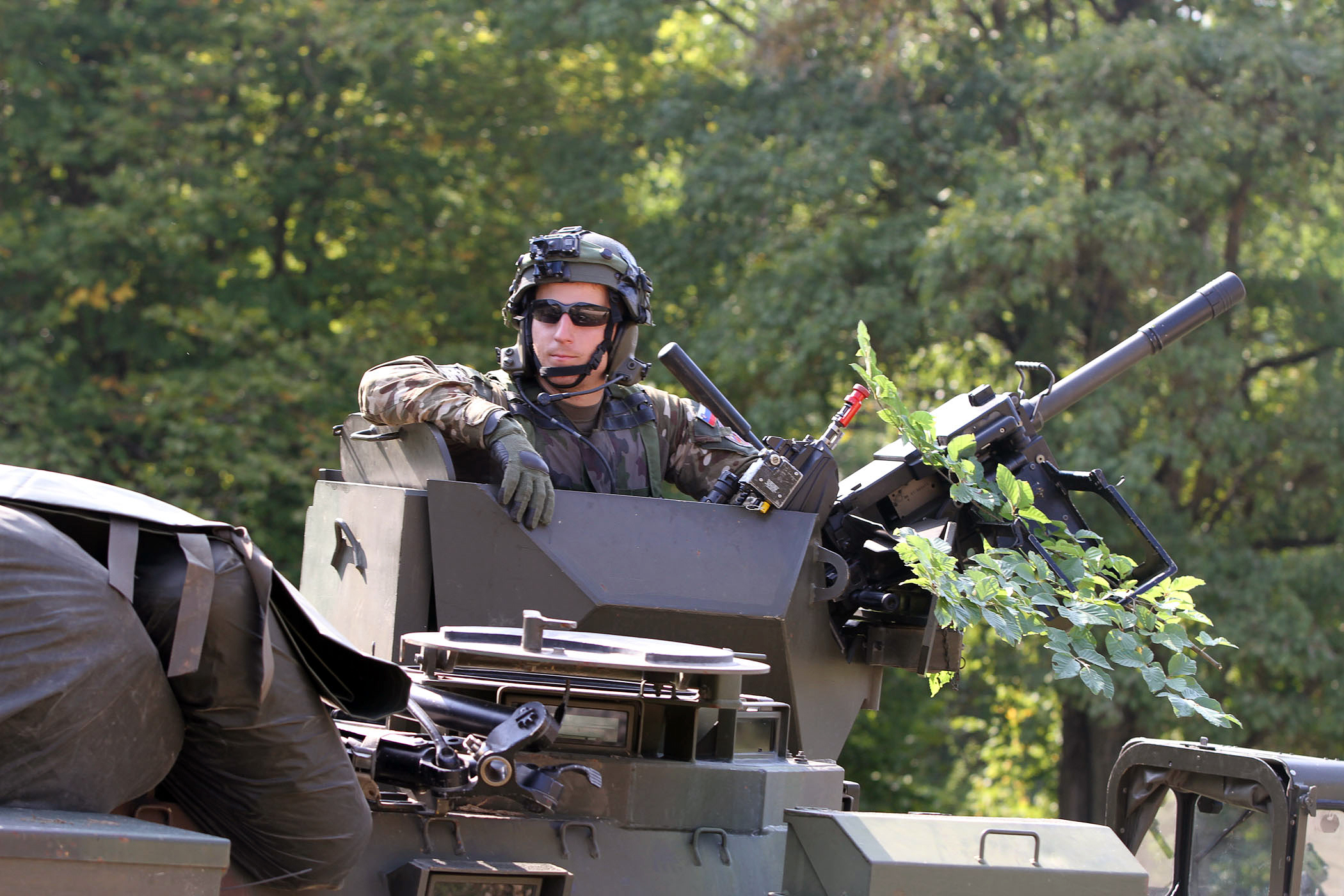 a man in the front of an army vehicle holding a rifle and standing next to other men