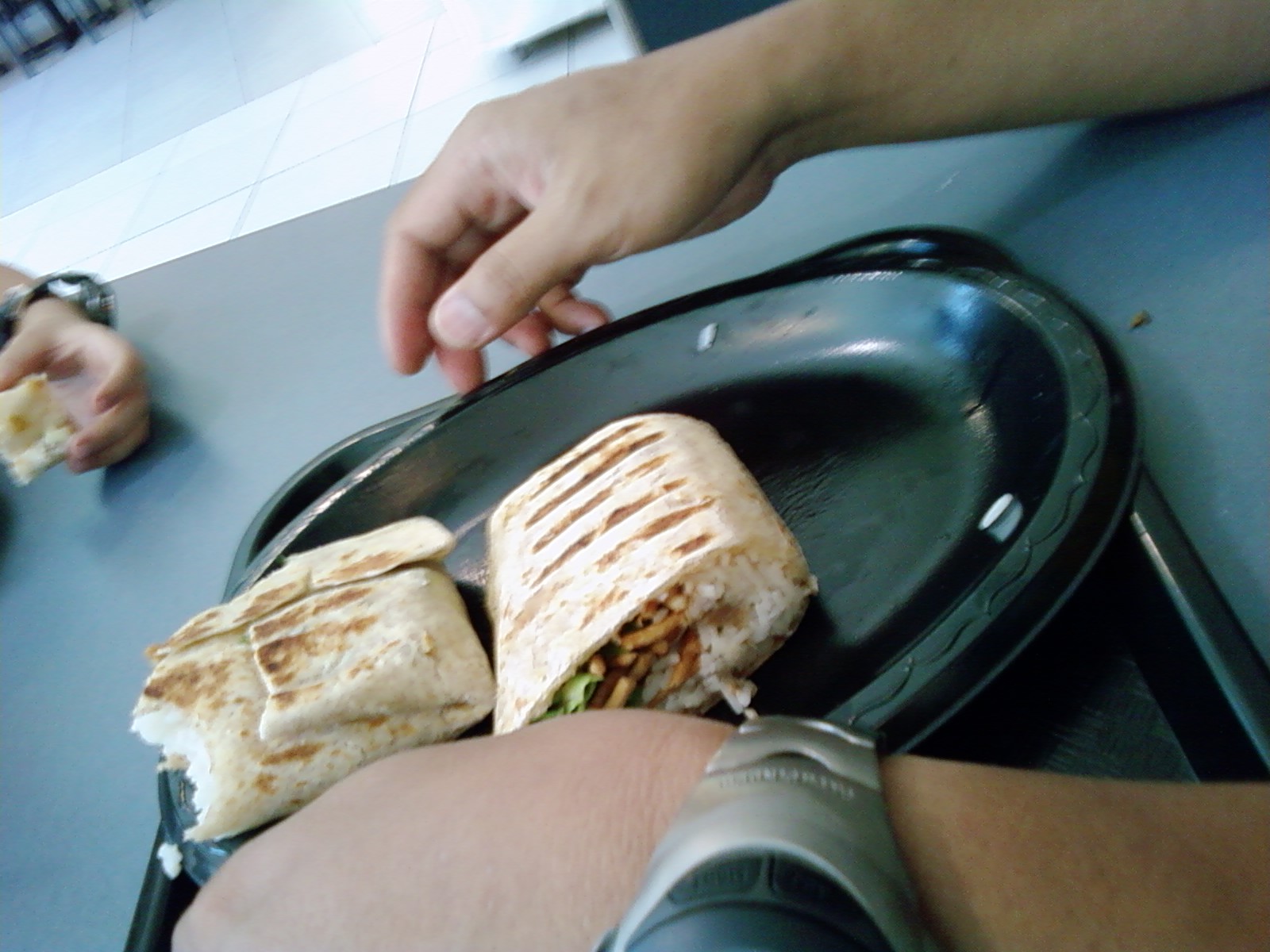 two hands reaching for a sandwich on a pan