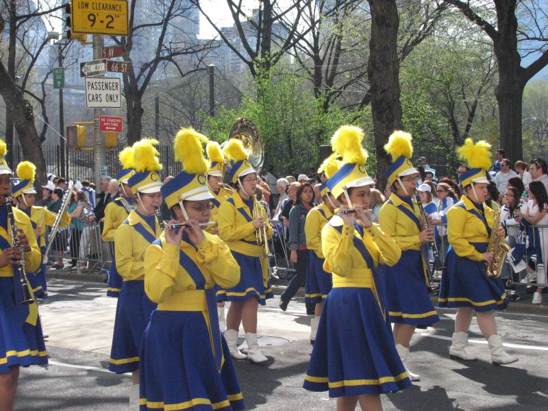 there are some women in blue and yellow uniform playing trombone