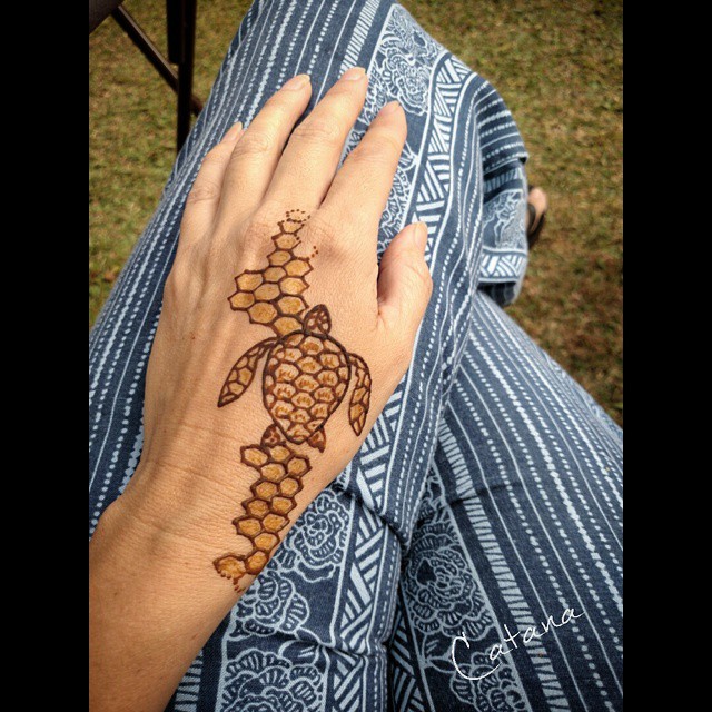 the hands are painted with henna tattoos that resemble turtles