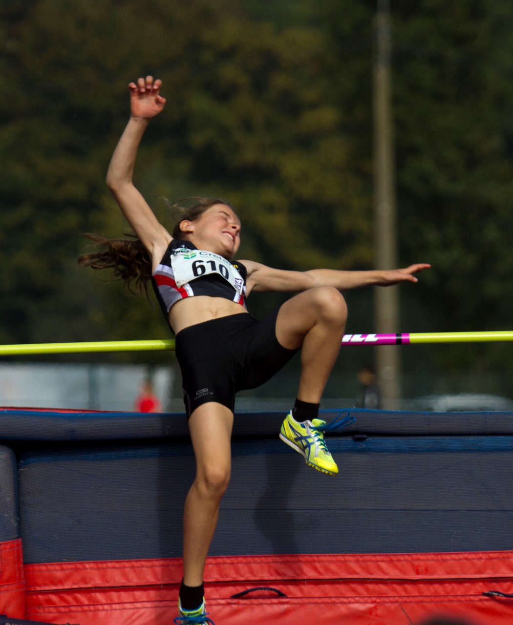 a female high jump jumper is doing her trick