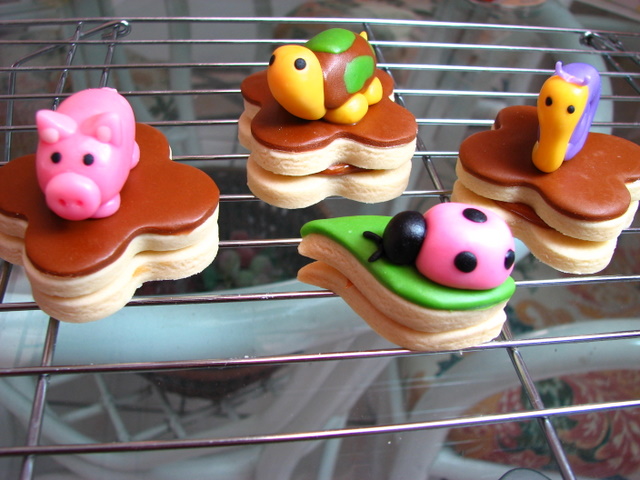 four cupcakes decorated like animals sit on the cooling rack