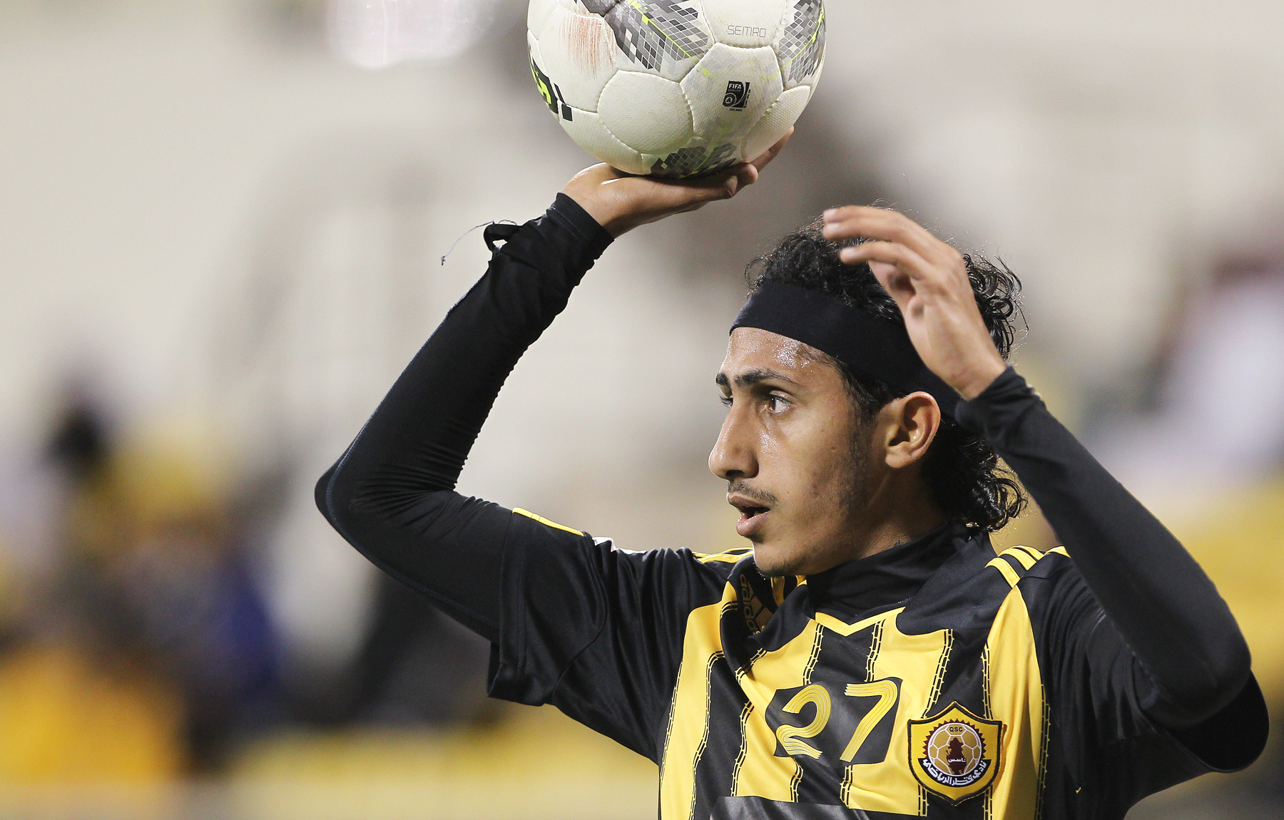 a soccer player holds up the ball while holding it in his hands