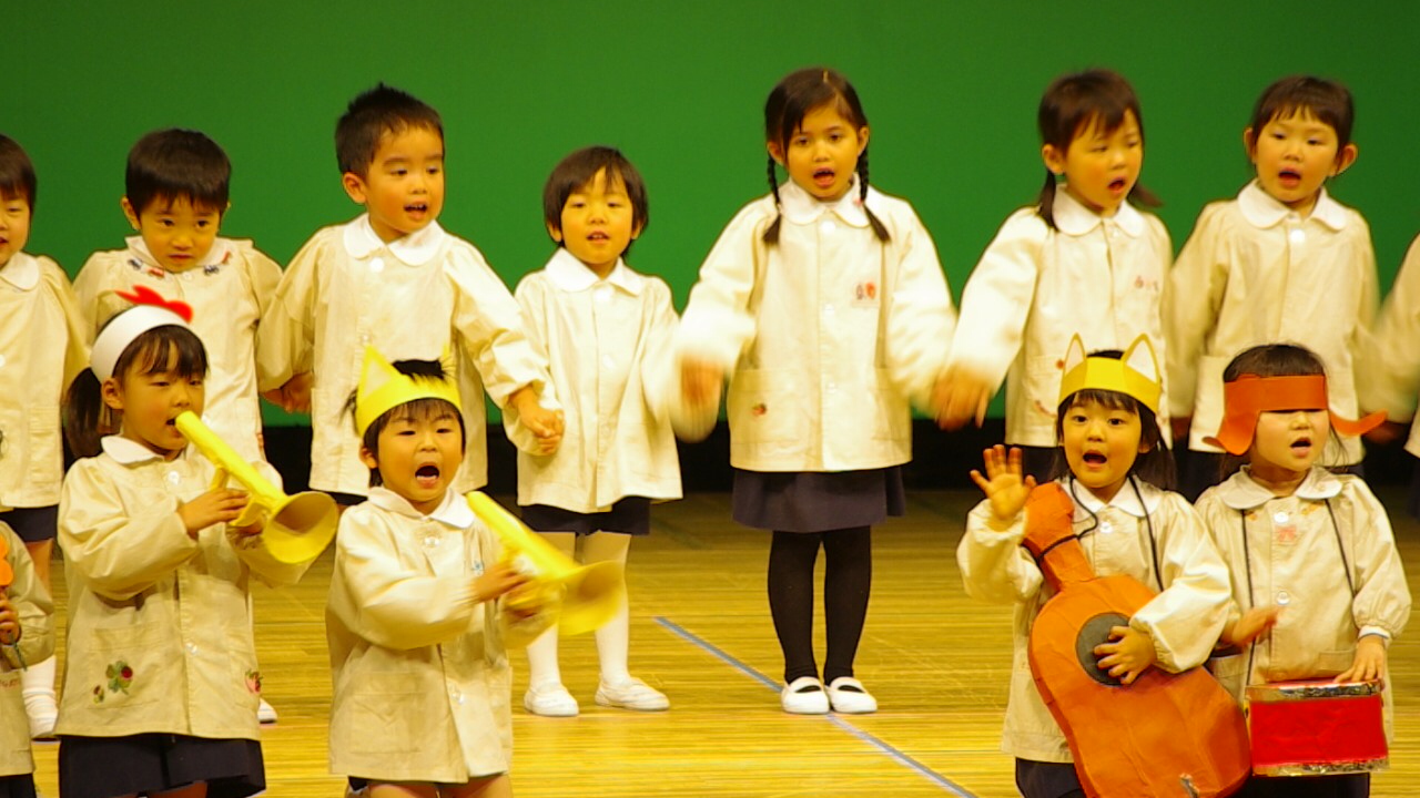 children in uniforms singing with paper props