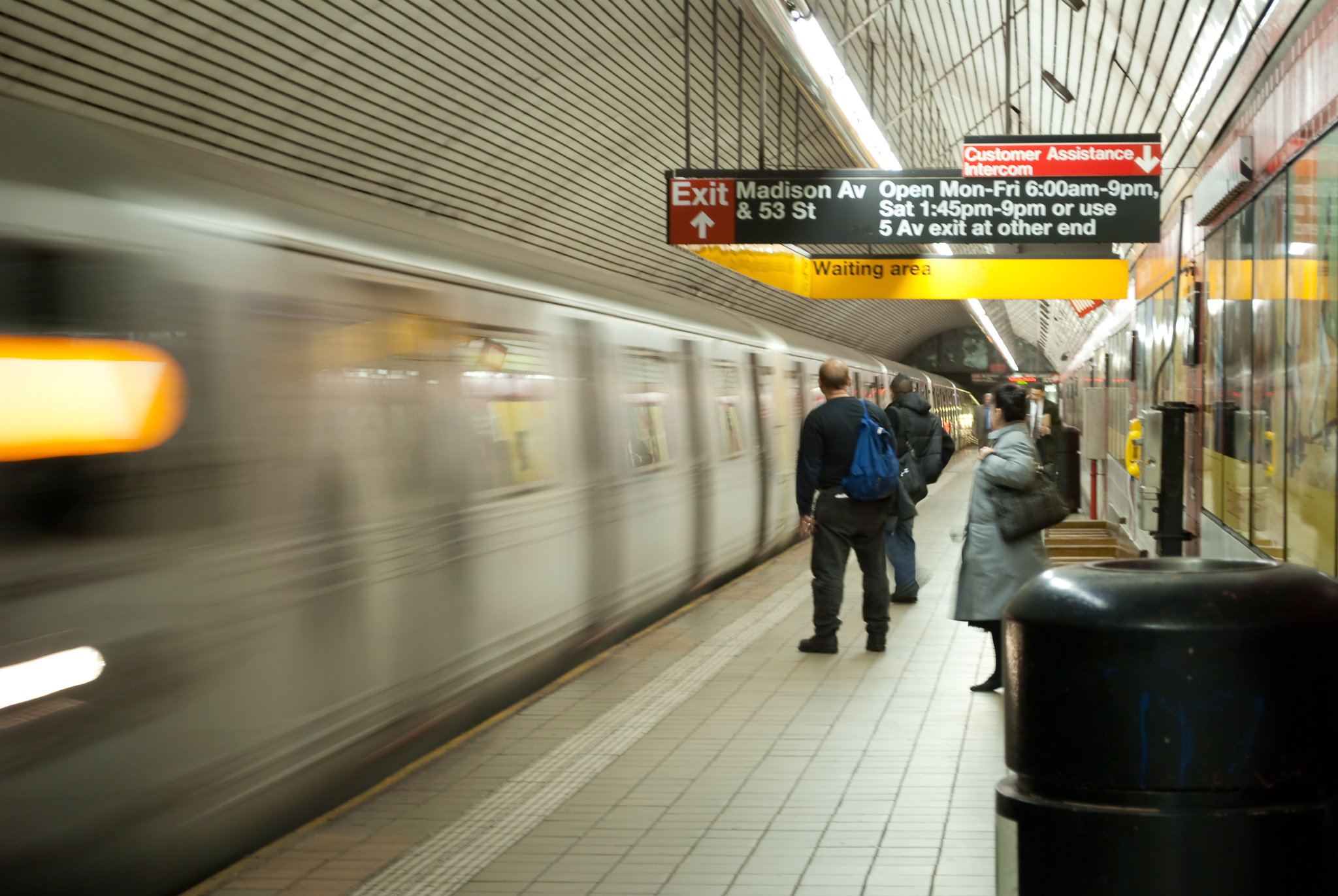 a person standing on a train platform as people walk past