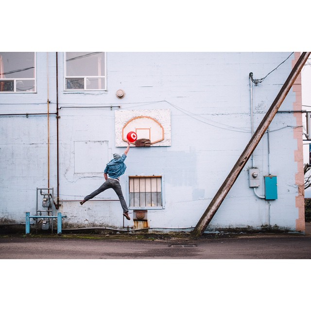 a man playing basketball on the street next to a building