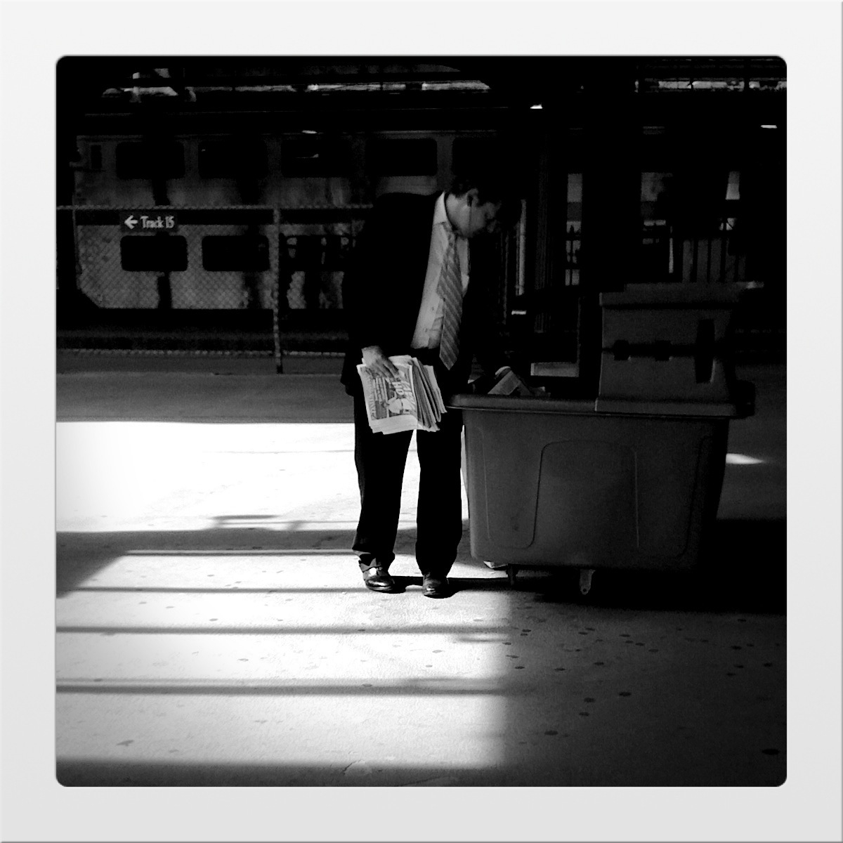 an older man standing in a station waiting for passengers to board