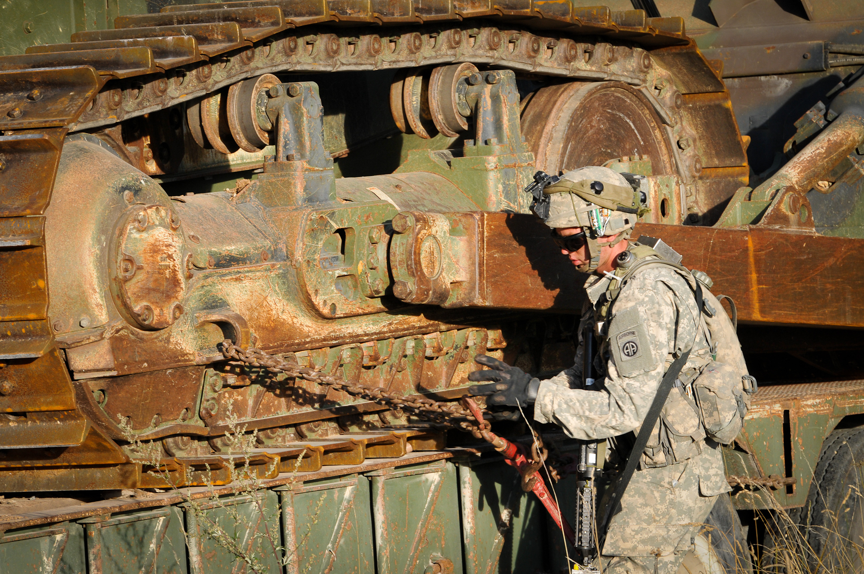 an old man in fatigues is next to a rusted out truck