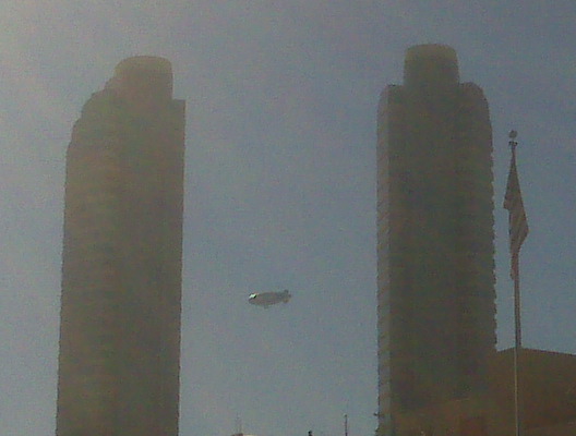 a big kite flying in the sky between two tall buildings