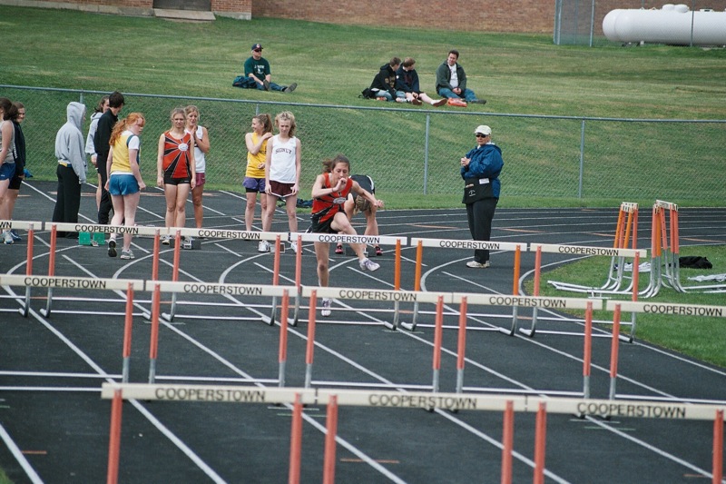 a group of s are sitting and standing in the line at an outdoor track