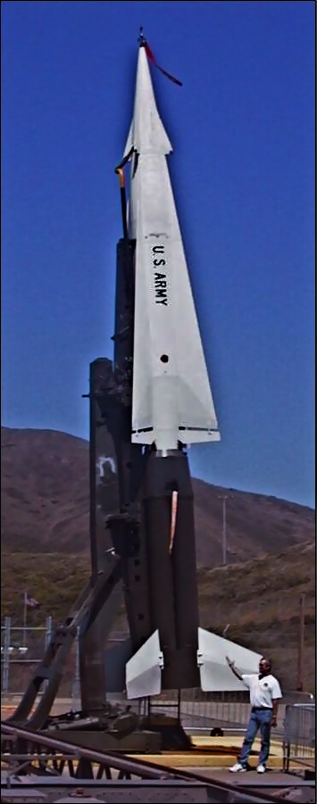 a man walks past a statue of a rocket