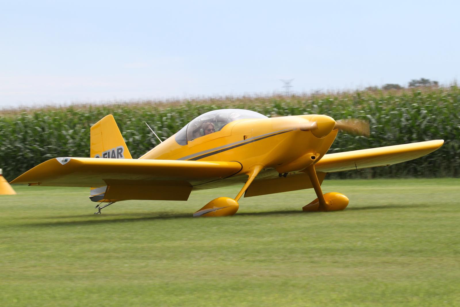 a small yellow plane sitting on top of a grass field