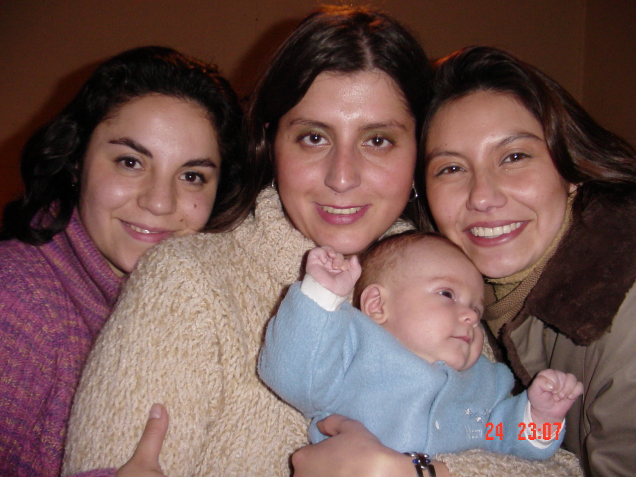 four people pose together for the camera with one holding a baby