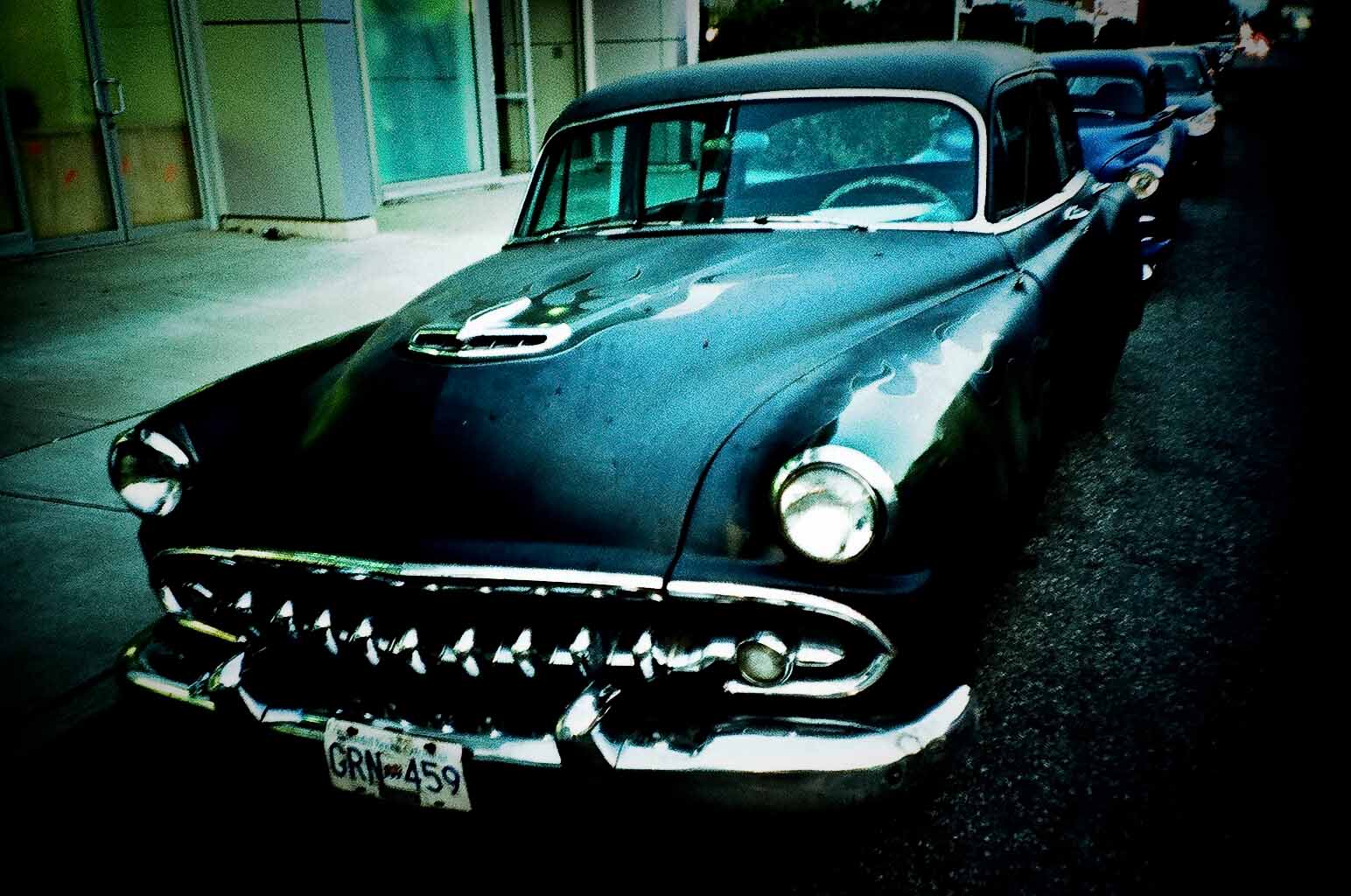 an old black car parked next to some buildings