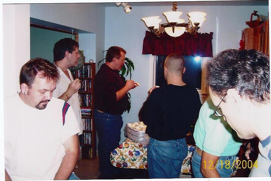 some men are standing in a room and one man is holding a cake